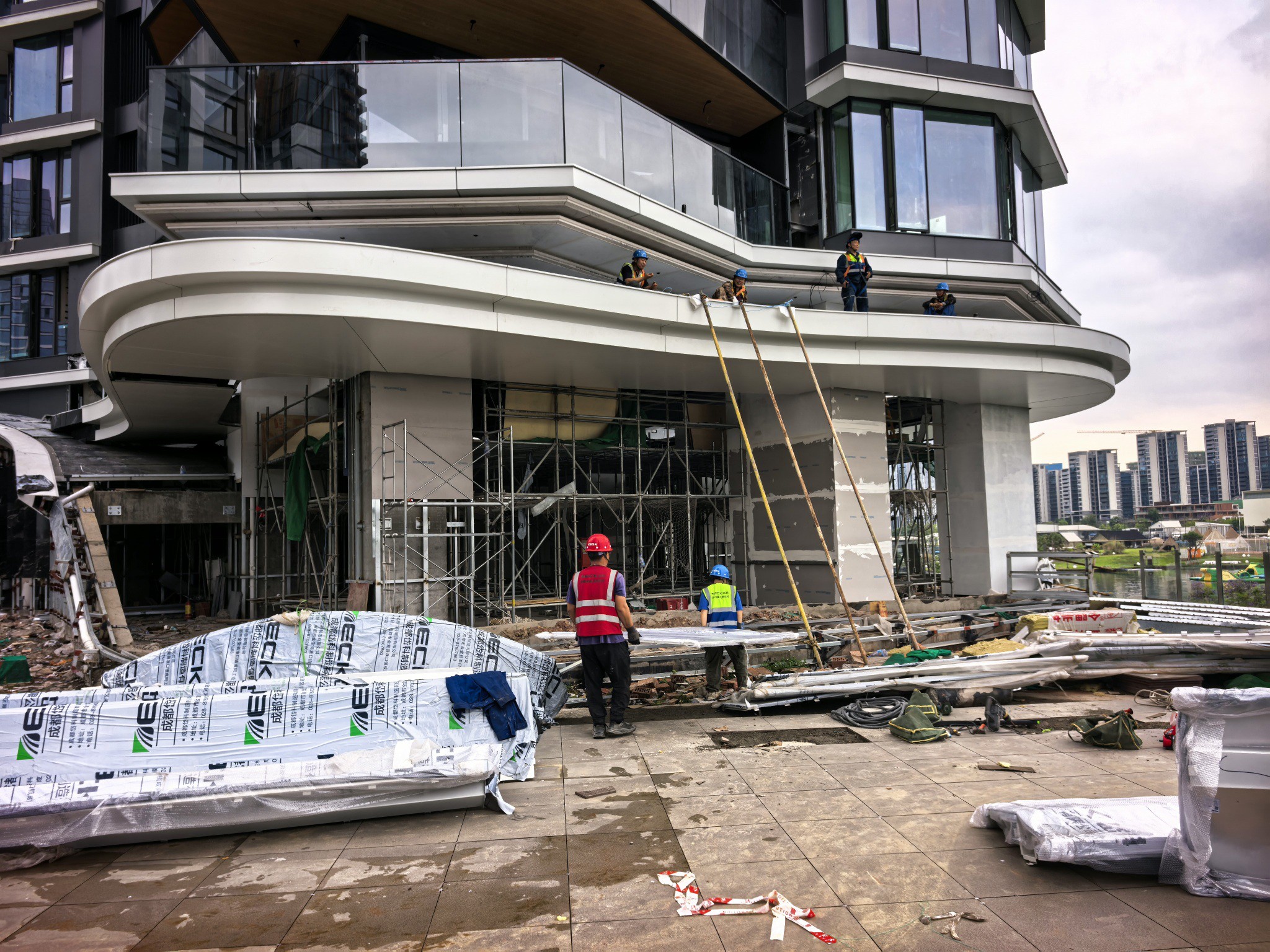 C7组团 施工现场——曲面造型建筑外立面，工人进行上层弧形铝板结构作业